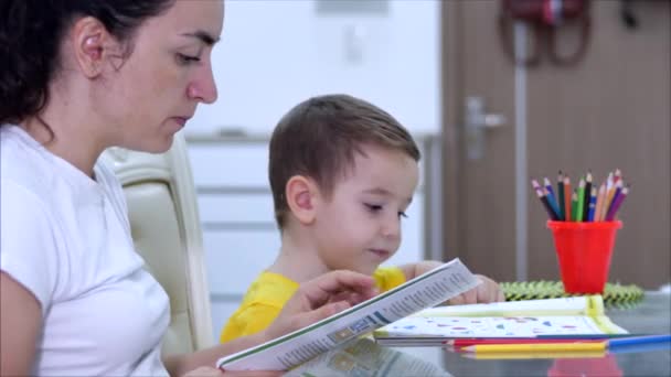 Ευτυχισμένη μητέρα μαθαίνουν χαριτωμένο αγοράκι παίζοντας επιτραπέζια παιχνίδια στο σπίτι, μαμά βοηθά το μωρό γιος να μάθουν να ζωγραφίζουν με μολύβια μαζί απολαμβάνουν τη δημιουργική διαδικασία. Covid-19, προστασία από ιούς, πανδημία στη λέξη — Αρχείο Βίντεο