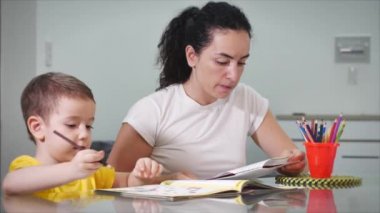 Mutlu aile annesi, dadı evde masa oyunu oynayan sevimli çocuğu öğreniyor, anne bebeğe kalemlerle resim çizmeyi öğrenmesinde yardımcı oluyor, yaratıcı sürecin tadını çıkarıyor..