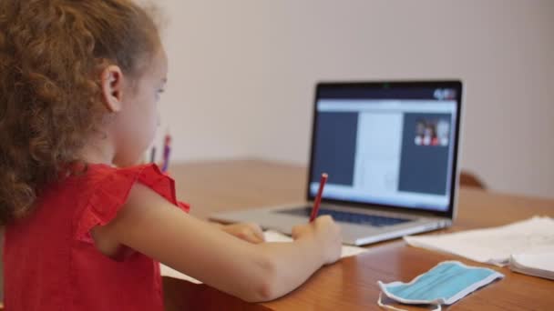 Afstandsonderwijs online onderwijs Schoolmeisje zit thuis aan haar bureau Voer een schoolopdracht uit met behulp van een digitaal tablet. School programma Online les met een leraar op de computer. — Stockvideo