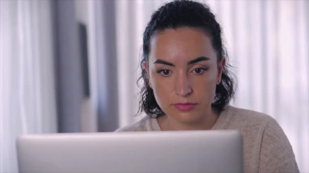 Joven mujer seria freelancer trabajando en una computadora portátil sentada en un sofá en casa, mujer de negocios escribiendo en una computadora portátil, chica enfocada usando una computadora para estudiar trabajo en línea en casa. Concepto de trabajo del empleado doméstico — Vídeos de Stock