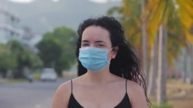 Coronavirus salgınından kalma maske takan genç bir kadının portresi sokakta koruyucu bir talep taşıyor. Kadın siyah elbisesinin önünde dikiliyor, uzaklara bakıyor. Sağlık ve güvenlik hayatı kavramını, Covid-19 'u, salgını kelime olarak kabul et..