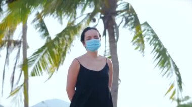 Coronavirus salgınından kalma maske takan genç bir kadının portresi sokakta koruyucu bir talep taşıyor. Kadın siyah elbisesinin önünde dikiliyor, uzaklara bakıyor. Sağlık ve güvenlik hayatı kavramını, Covid-19 'u, salgını kelime olarak kabul et..