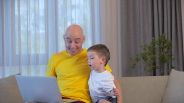 Evde dizüstü bilgisayarda çalışan serbest çalışan, iş adamı dizüstü bilgisayarı kullanan, evde çalışmak için bilgisayar kullanan, küçük oğlu ona yaklaşır ve çalışmaktan sıkılan babasına sarılır..