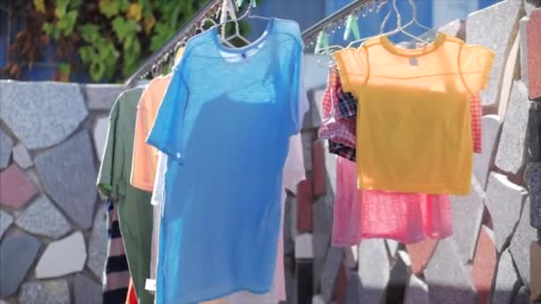 Após a lavagem, as roupas íntimas e roupas secas após a lavagem no varal, camisetas, roupas rosa, amarelo, cores brilhantes são secas no varal ao ar livre em tempo ensolarado . — Vídeo de Stock