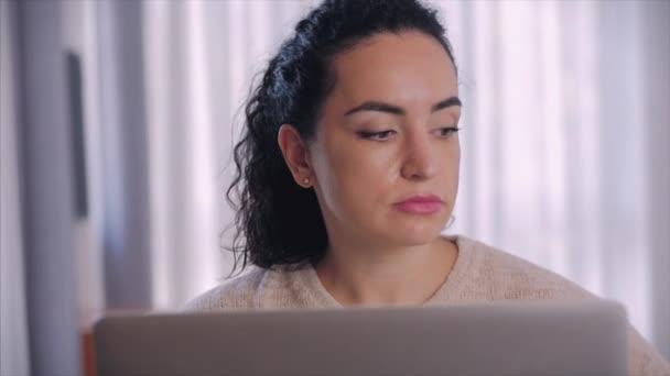Portrait caring caucásico freelancer mujer que se pone gafas antes de empezar a trabajar en un ordenador portátil, mirando a la cámara. Empleada mujer seria mira a la cámara y comienza a trabajar en un ordenador portátil . — Vídeos de Stock