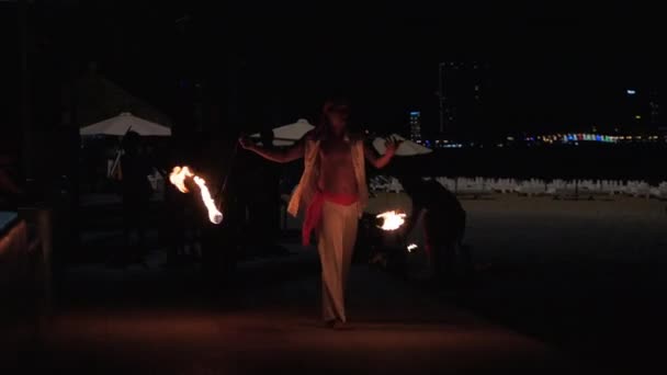 Artistas profesionales organizaron un espectáculo nocturno en la playa de arena, entreteniendo a los visitantes de cafés y restaurantes junto al mar agitando bolas de fuego en Nha Trang, Vietnam, Mayo 8, 2020 . — Vídeos de Stock