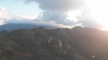 Denizin arka planında ve küçük balıkçı mercanlarında bir dağın insansız hava aracı görüntüsü. Vahşi yaşam manzarası, dramatik gökyüzü, bulutlar yüzüyor.