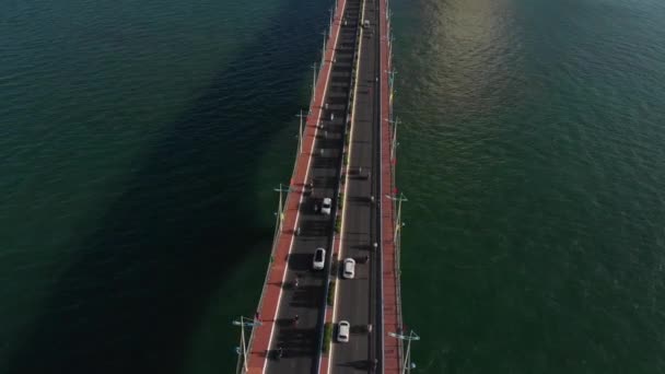Skytte antenn obemannad flygning från toppen av staden bron med bilar och motorcyklar mot bakgrund av det vackra havet i havet och stora stadsbyggnader. Bro och motorväg. — Stockvideo