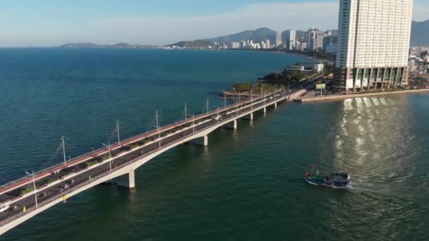 Şehir köprüsünün üst kısmından okyanus ve büyük kasaba binalarının arka planına karşı arabalarla ve motorsikletlerle havadan insansız uçuşlar yapmak. Köprü ve şehir otoyolu. — Stok video