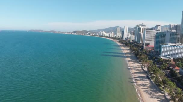 Aerial drones take a beautiful view of the city from a birds eye view with skyscrapers or tall buildings against the backdrop of a beautiful blue sea. 4K. — Stock Video