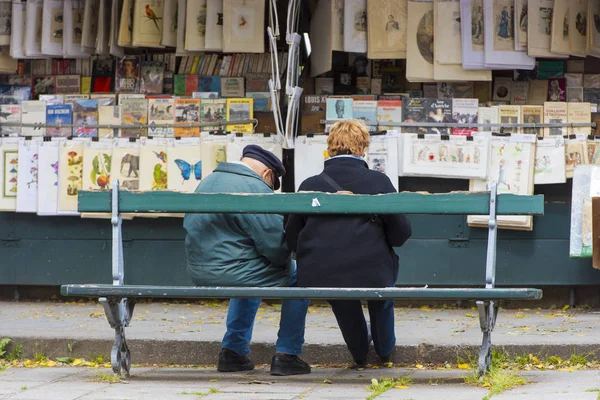 Pessoas em um banco em um mercado de livros em segunda mão no cais do rio Sena perto da catedral Notre Dame em Paris — Fotografia de Stock