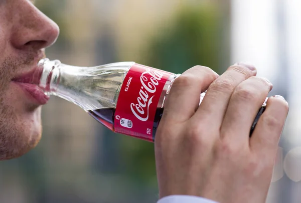 En man dricker den berömda drycken Coca Cola från glasflaska — Stockfoto