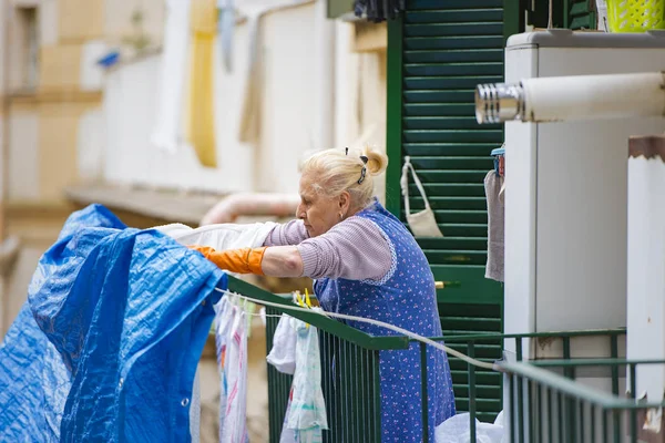 Idosos italiano mulher pendurado para fora roupas em Nápoles — Fotografia de Stock