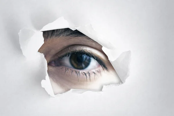 Menschliches Auge durch das Loch des weißen Papiers, Spion-Auge — Stockfoto