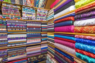 Asya pazarında renkli tekstil veya kumaş, kumaş ruloları ve tekstil rafları