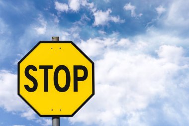 Mavi gökyüzüne karşı sarı sekizgen yol işareti