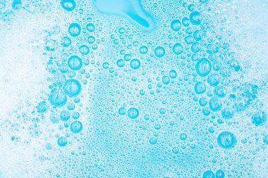 Su yüzeyinde köpüklü beyaz köpük, sabun ve mavi banyoyla yıkama tozu, soyut şeffaf arka plan kabarcığı.