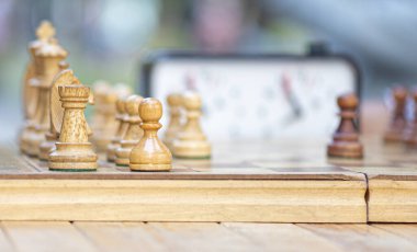 Satranç, klasik, eski, tahta satranç tahtasıyla yakın plan satranç tahtası. İnsanlar şehir parkında satrançla oynuyor. 