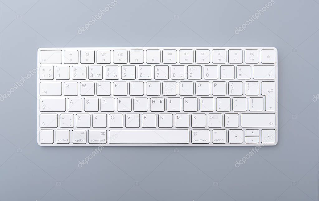 Close-up white keyboard on gray desk, top view of modern computer keyboard isolated on gray background 