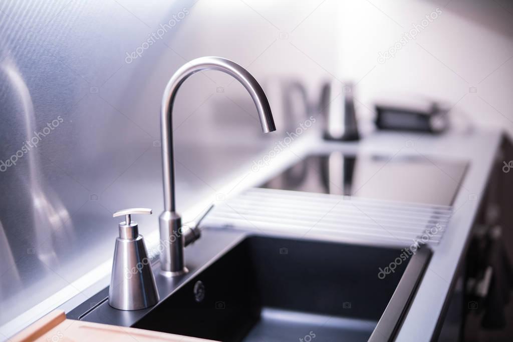 Black stone sink and water faucet in new modern kitchen interior.