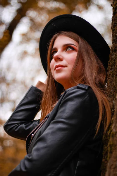 Menina de outono elegante no parque. Camisola, chapéu e casaco de couro — Fotografia de Stock