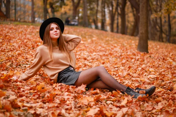 Herfst meisje in het park. Trui, hoed en leren rok. Stijlvol — Stockfoto