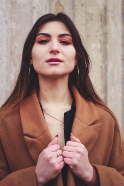 Siyah elbiseli ve uzun kahverengi ceketli bir manken. Siper. Tarz. Moda.