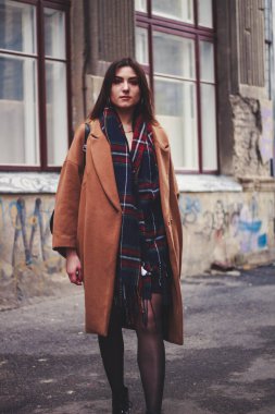 Siyah elbiseli ve uzun kahverengi ceketli bir manken. Siper. Tarz. Moda.