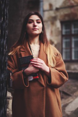 Siyah elbiseli ve uzun kahverengi ceketli bir manken. Siper. Tarz. Moda.