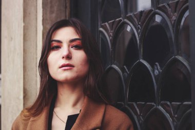 Siyah elbiseli ve uzun kahverengi ceketli bir manken. Siper. Tarz. Moda.