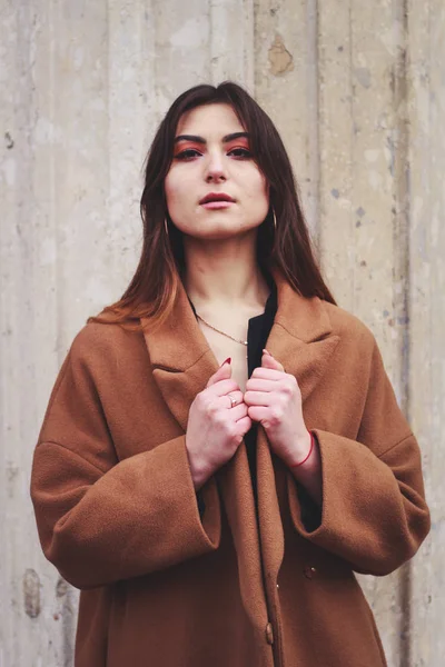Model in zwarte jurk en lange bruine jas. Een moersleutel. Stijl. Mode — Stockfoto