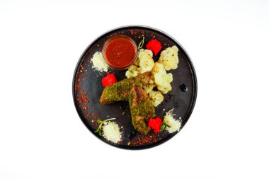 Karnabahar garnitürlü domuz filetosu. Siyah tabak. Gri b