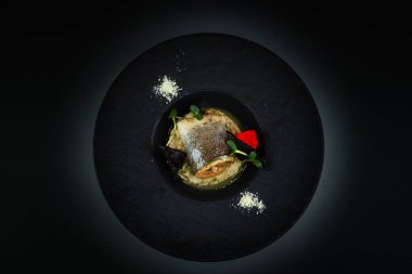 Deniz kabuğu balığı ve mantar püresi. Siyah tabak. Karanlık arka plan. Mo!