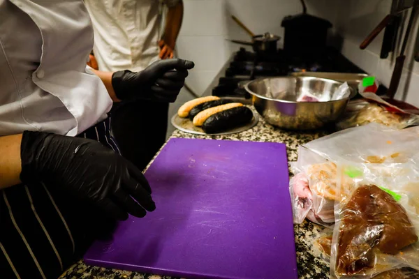 Hot dog da cucina con panino nero e polpo. In cucina. capo cuoco . — Foto Stock