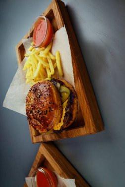 İki burger, sığır eti, tavuk ve patates kızartması. Tahta tabak. G