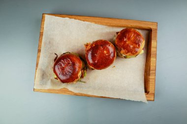 Biftek, tavuk ve soğan halkalı üç mini burger. Tahta pil!