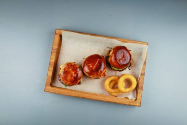 Biftek, tavuk ve soğan halkalı üç mini burger. Tahta pil!
