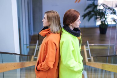 Uzun kapüşonlu floresan sarısı ve turuncu giyen iki kız. Sıcak b