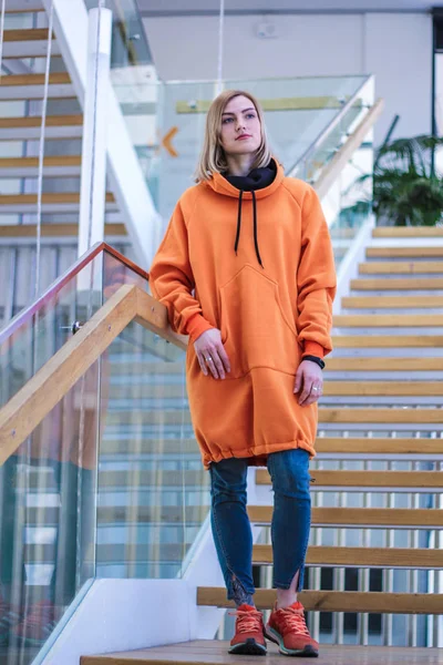 Chica en una larga sudadera con capucha de color amarillo fluorescente. Suéter cálido y brillante. U — Foto de Stock