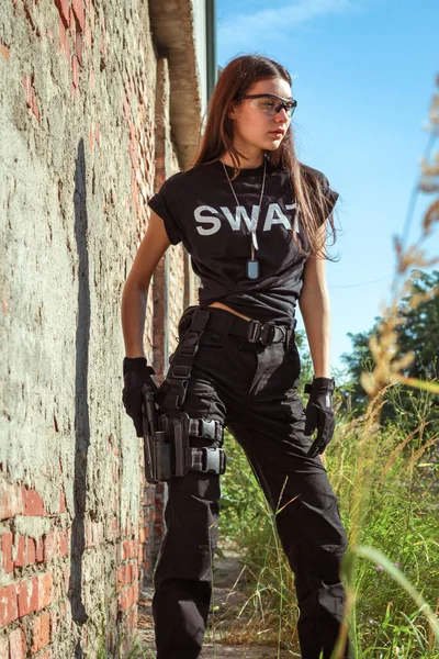Girl in tactical clothes with a gun. Military woman. Black T-shirt and pants. Holster.SWAT