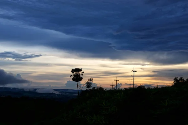 Puesta de sol con nubes de lluvia y silueta poste de electricidad — Foto de Stock