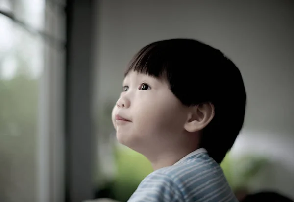 Tatlı küçük çocuk pencereden bakıyor — Stok fotoğraf