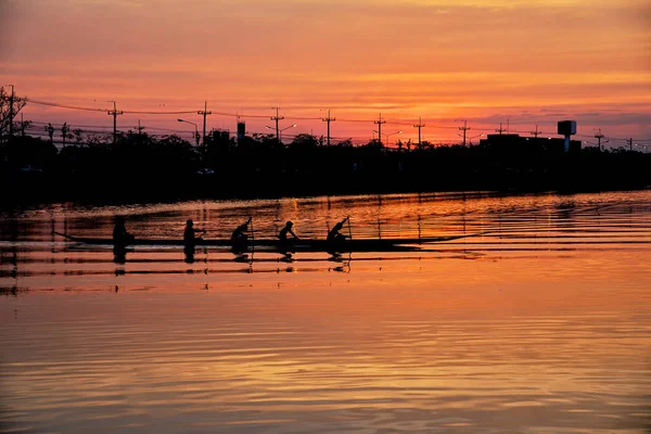 团队工作的年轻男子在一排船映衬在日落 — 图库照片
