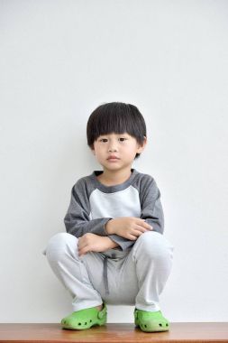 Beyaz duvar Isolated katta oturan küçük çocuk 