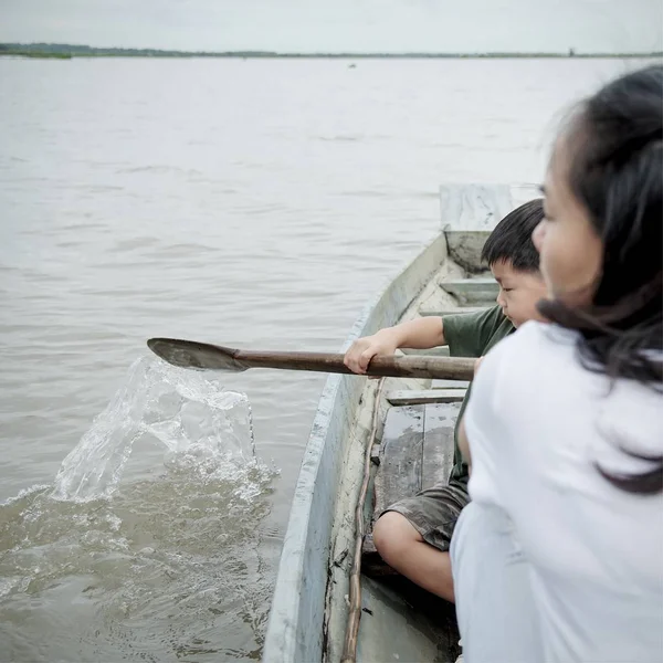 Liten pojke rodd i en träbåt på sjön: närbild — Stockfoto