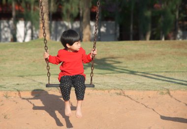 Küçük Asyalı çocuk oturma ve koltuk salıncak asılı seyir