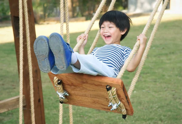 Glücklicher kleiner asiatischer Junge lacht und schwingt auf einer Schaukel — Stockfoto