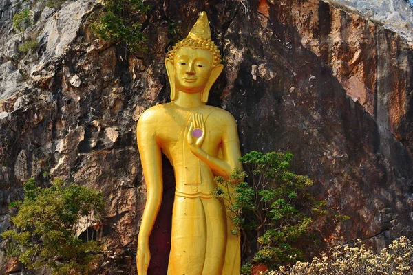 Estatua de piedra dorada de un buda sobre fondo de montaña —  Fotos de Stock