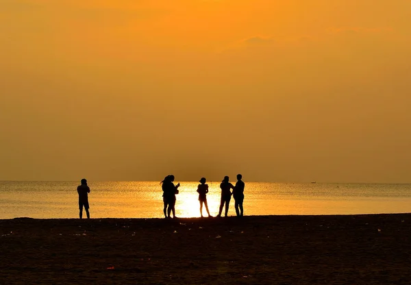 Silhouette of  people on beach has sunset background — Stock Photo, Image