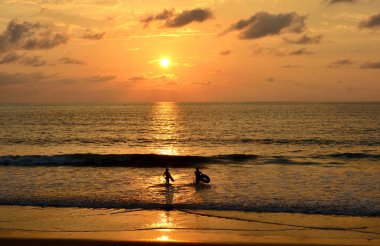 Günbatımı plaj manzarasına sahiptir siluet insanlar deniz oynuyor